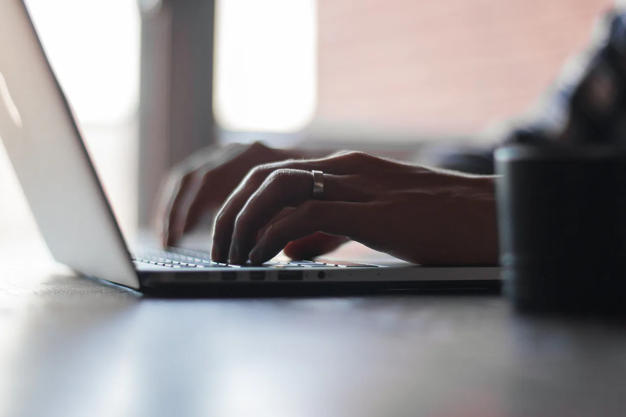 Manos escriben en el teclado de un portátil