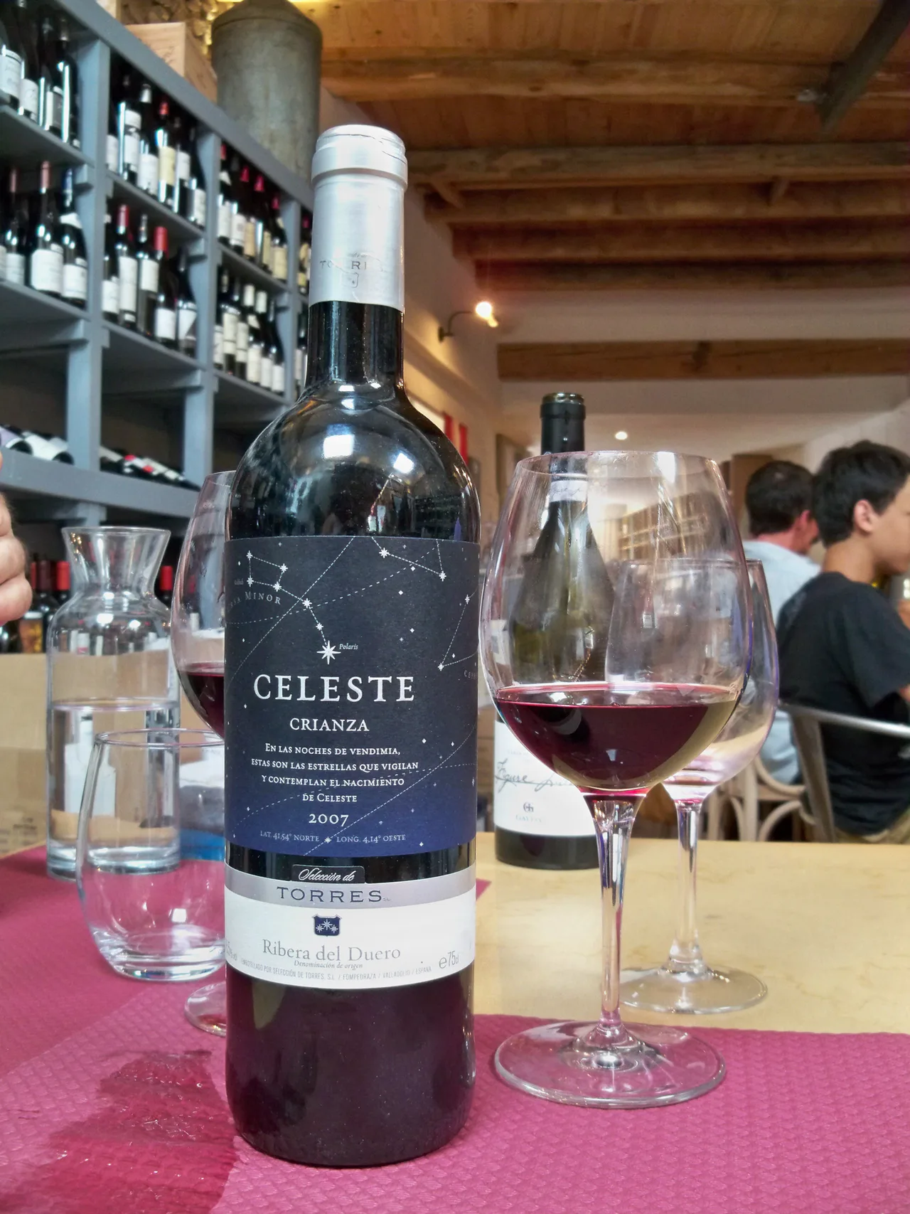 Botella de Celeste Crianza 2007 con una etiqueta de estrellas, junto a copas de vino