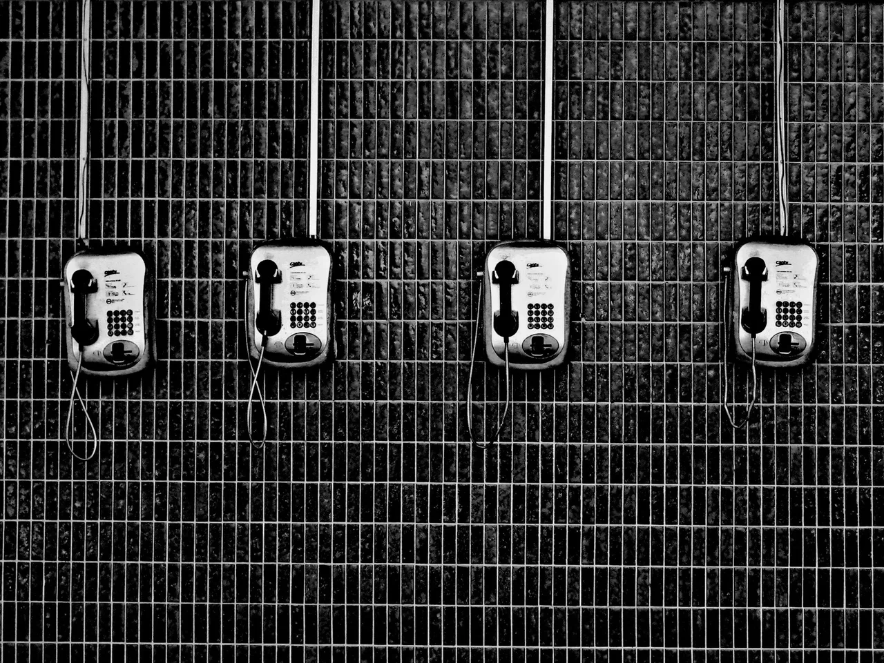 Teléfonos antiguos alineados en una pared oscura