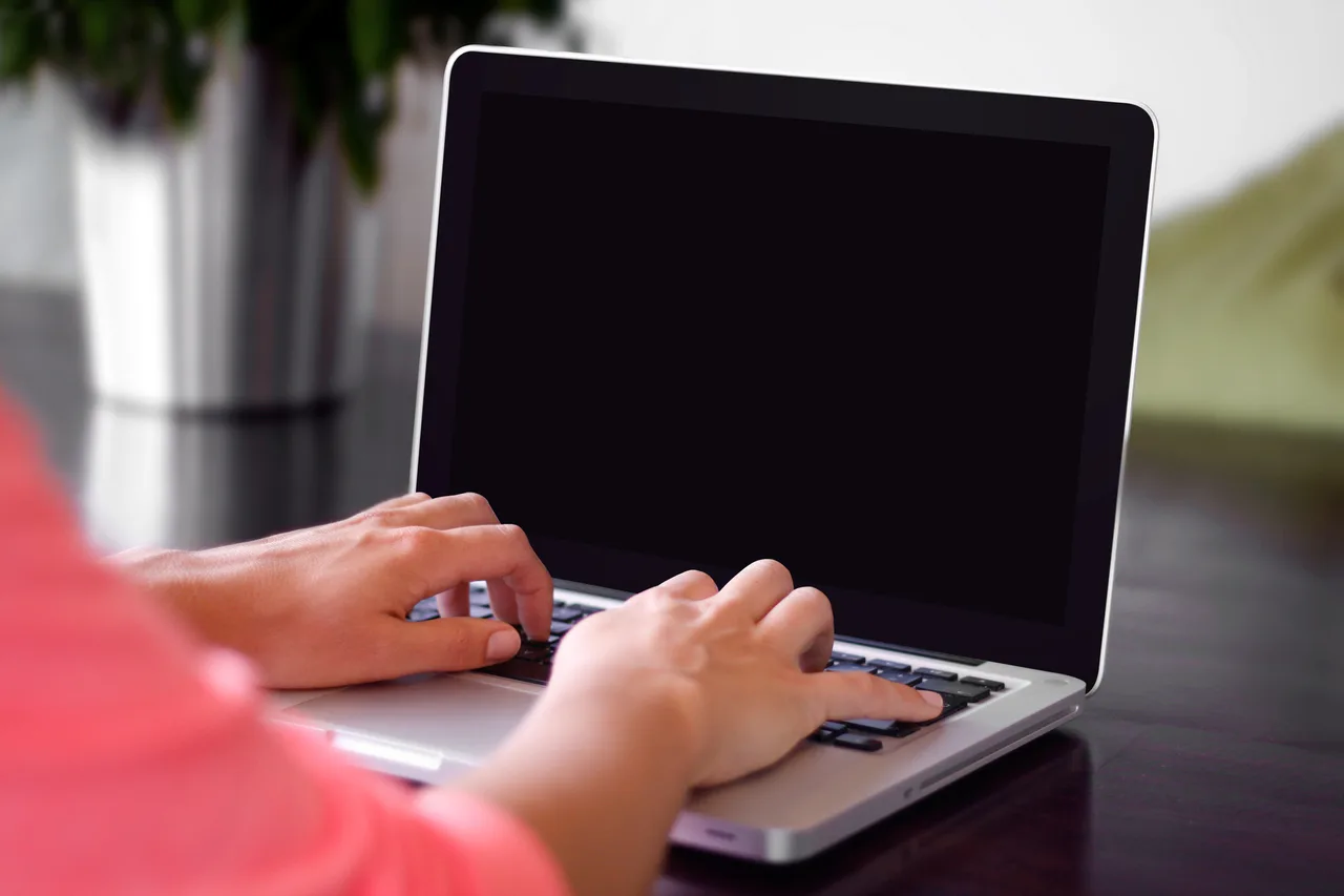 Hands typing on a laptop keyboard at a table.
