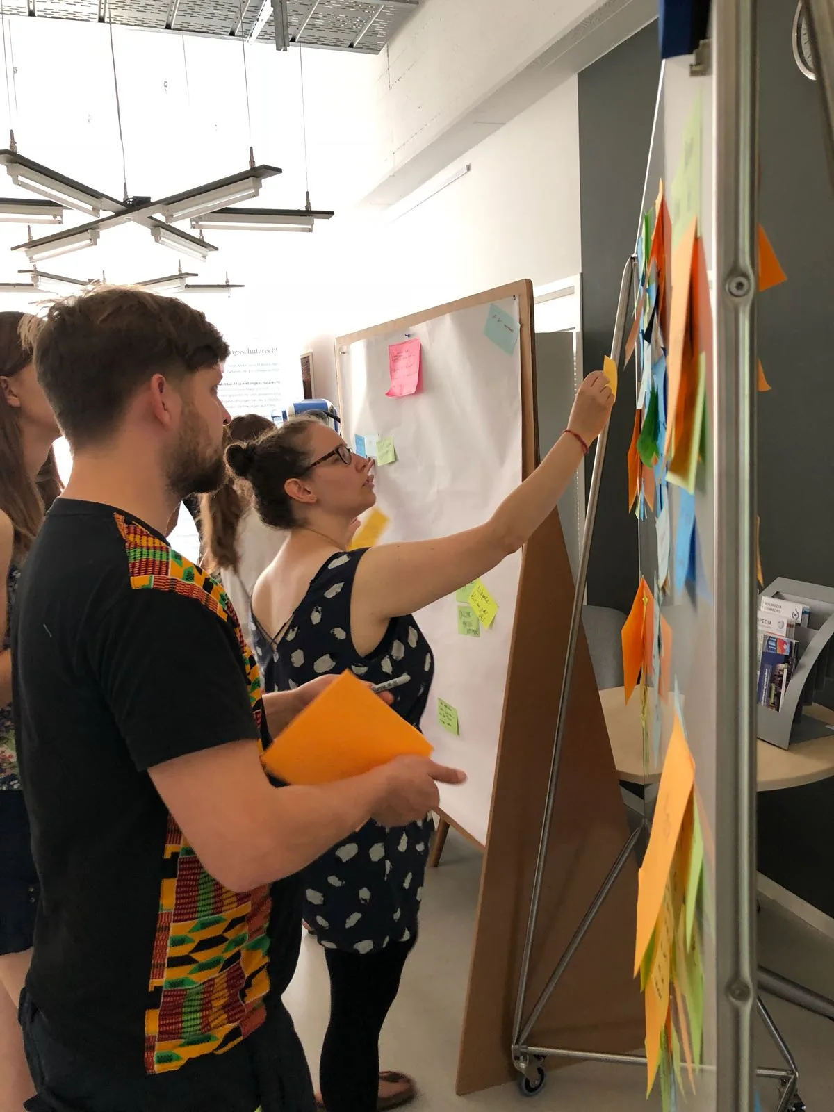 Participants place sticky notes on a board during a design thinking workshop.
