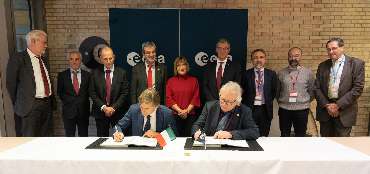 Dos personas firman documentos en una mesa durante una ceremonia de ESA y OHB.