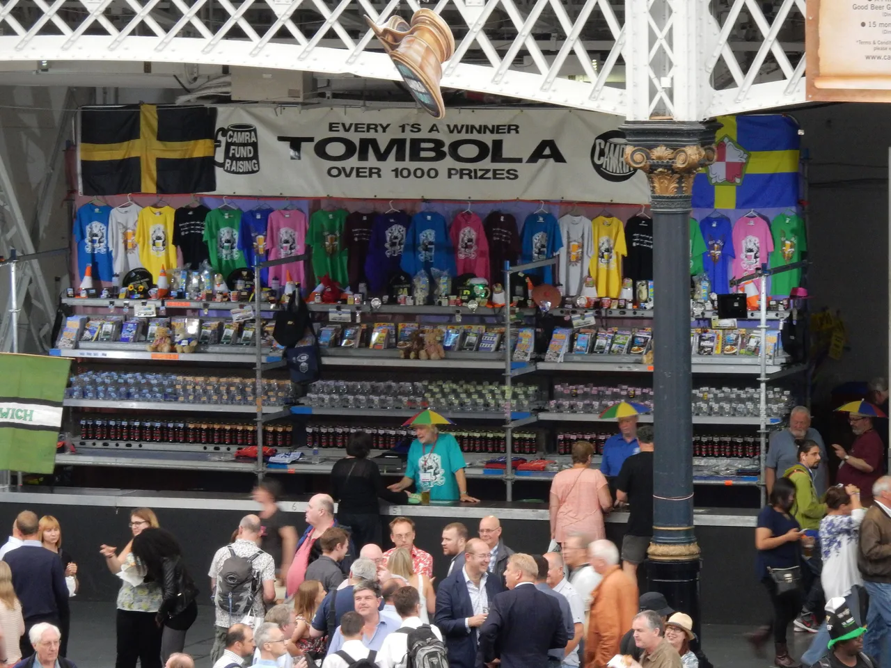 A tombola stall displays prizes in front of visitors at a beer festival.