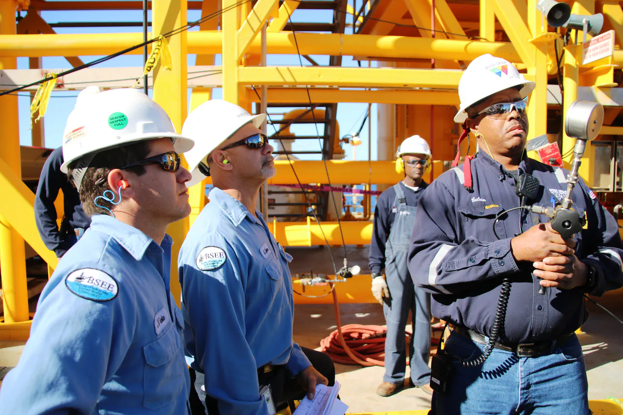 Inspectores de BSEE y un trabajador comprueban equipos durante una prueba de presión