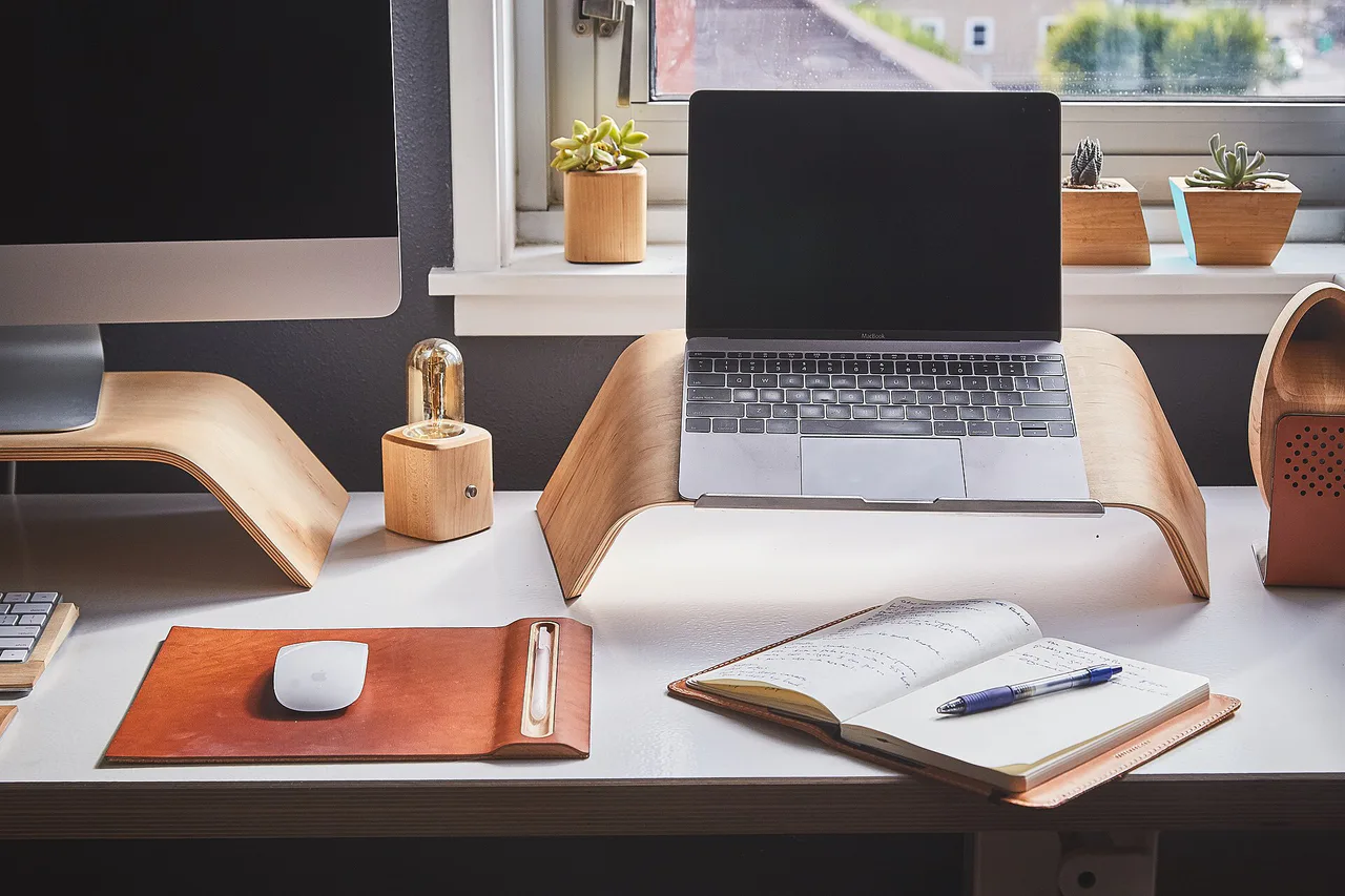 Portátil, cuaderno y material de escritura en una mesa