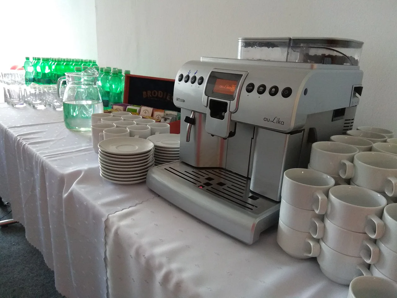Saeco auLika automatic coffee machine beside cups on an office refreshment table