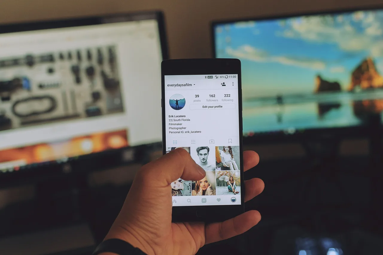 Una mano sostiene un teléfono que muestra un perfil de Instagram con fotografías.