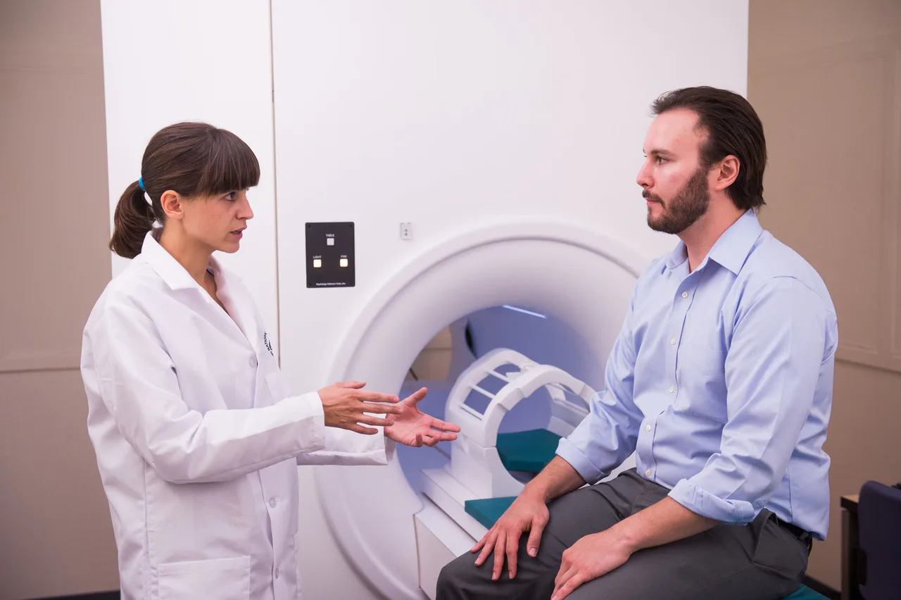 A researcher prepares a participant beside diagnostic equipment.