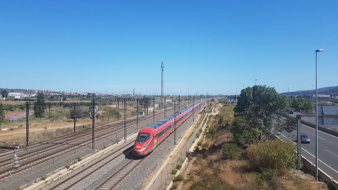 A red iryo train passes through Quatre Camins towards Barcelona