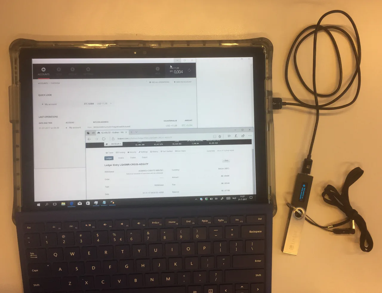 A laptop shows transfer records with a Ledger hardware wallet connected by cable beside it.