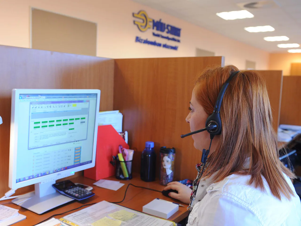 An operator at a MÁV customer-service centre using a headset and computer