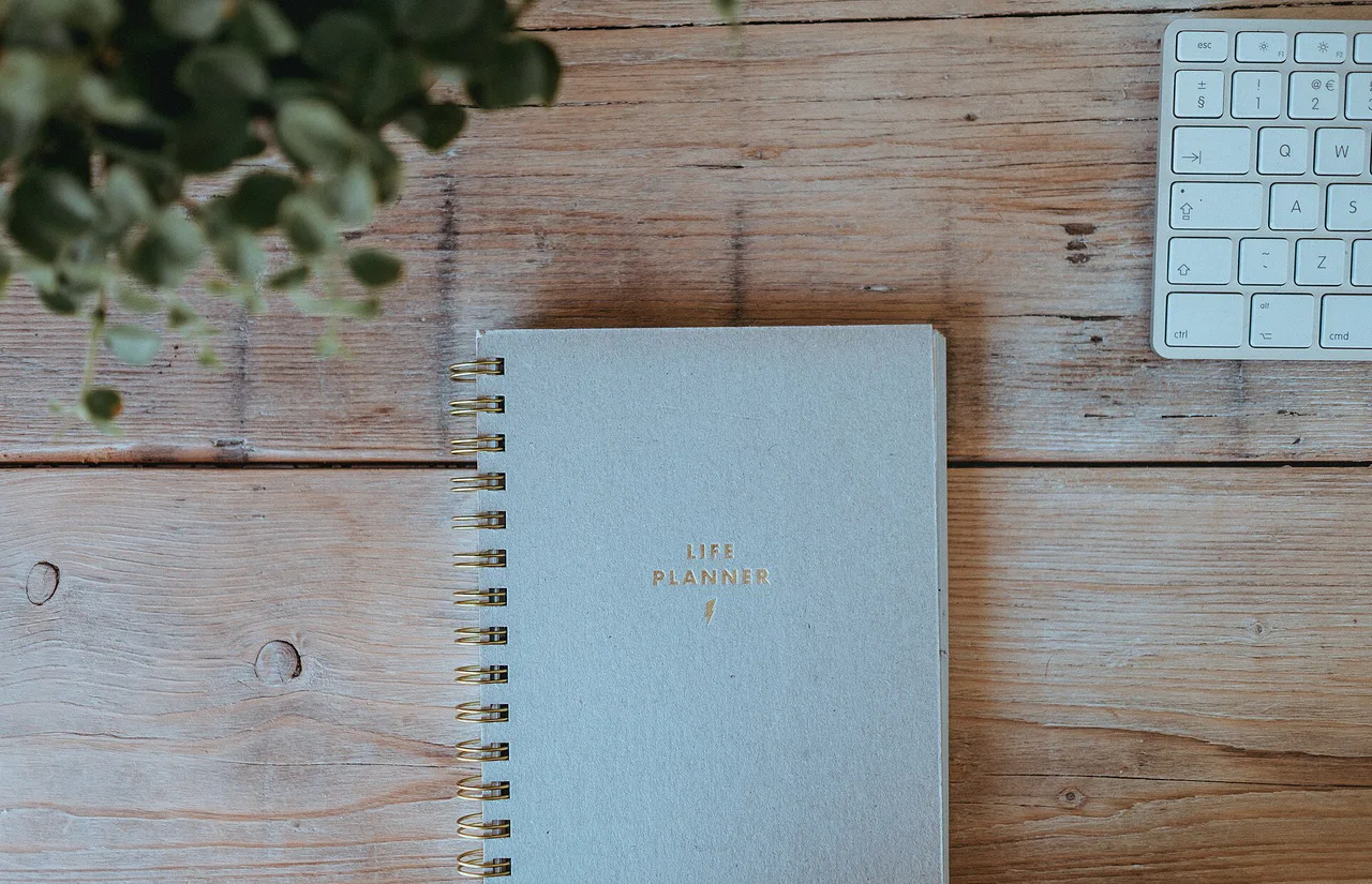 Cuaderno de planificación junto a un teclado sobre una mesa de madera