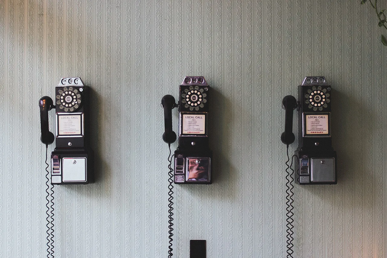 Tres teléfonos antiguos colgados en una pared