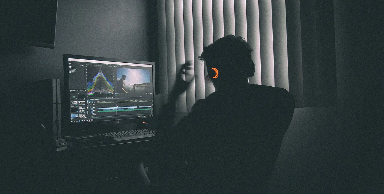 A person edits video on a screen showing a timeline and colour controls.