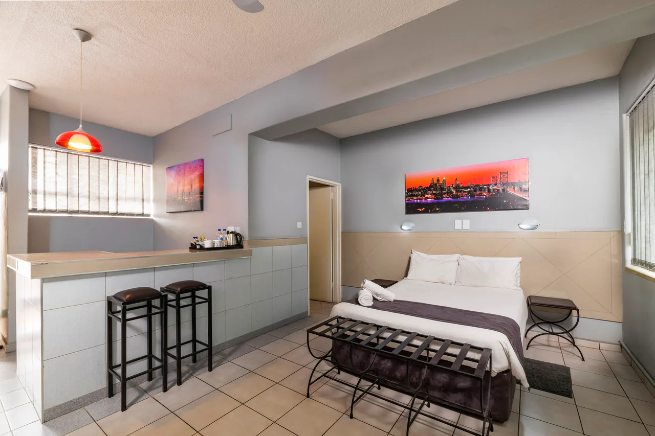 Hotel room with a double bed, a desk and a luggage stand