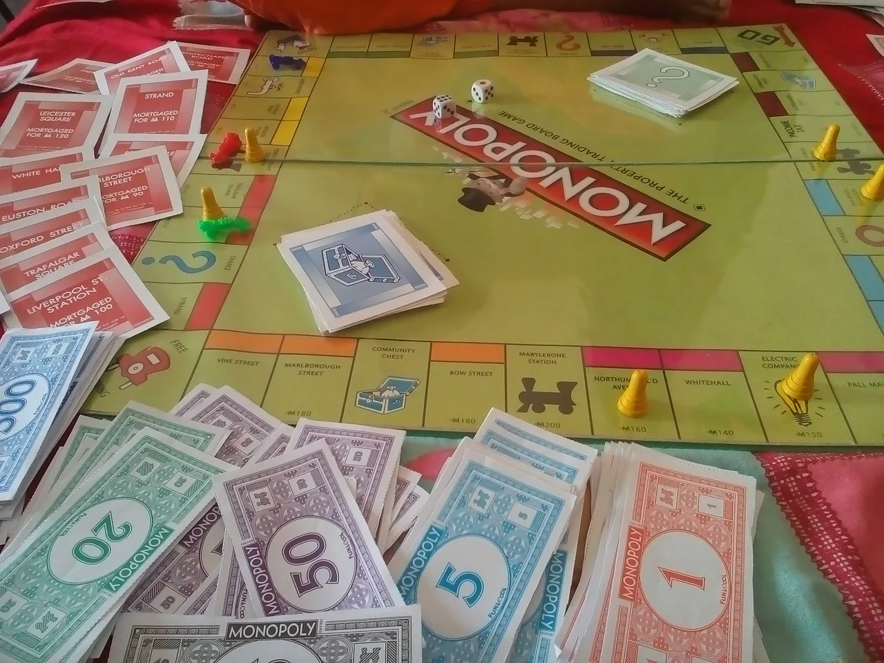 A physical MONOPOLY board with banknotes, cards, dice and colored playing pieces.