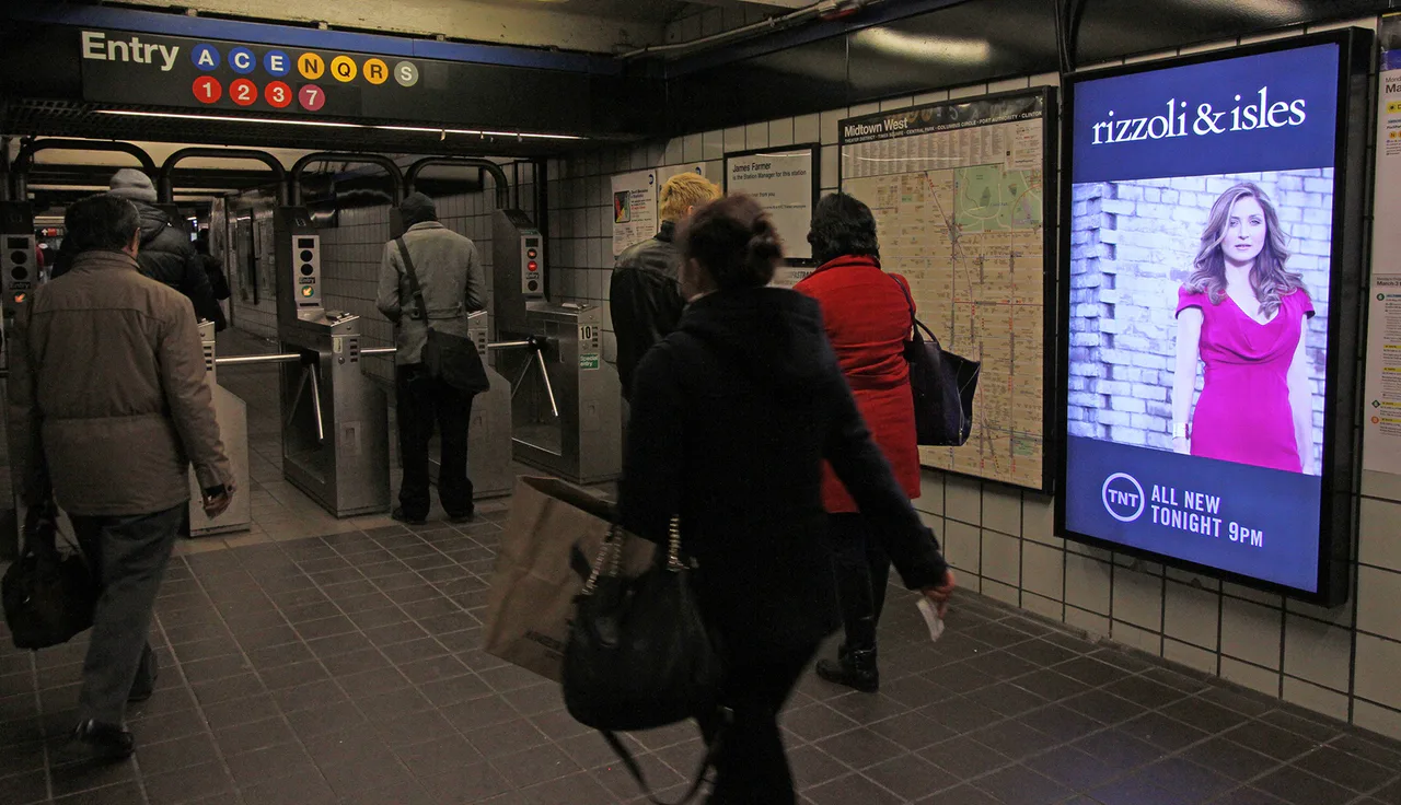 Una pantalla publicitaria digital junto a los tornos de una estación de metro de Nueva York.
