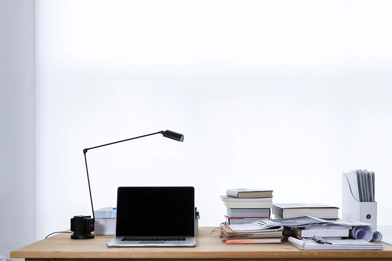 Portátil y libros apilados sobre una mesa blanca