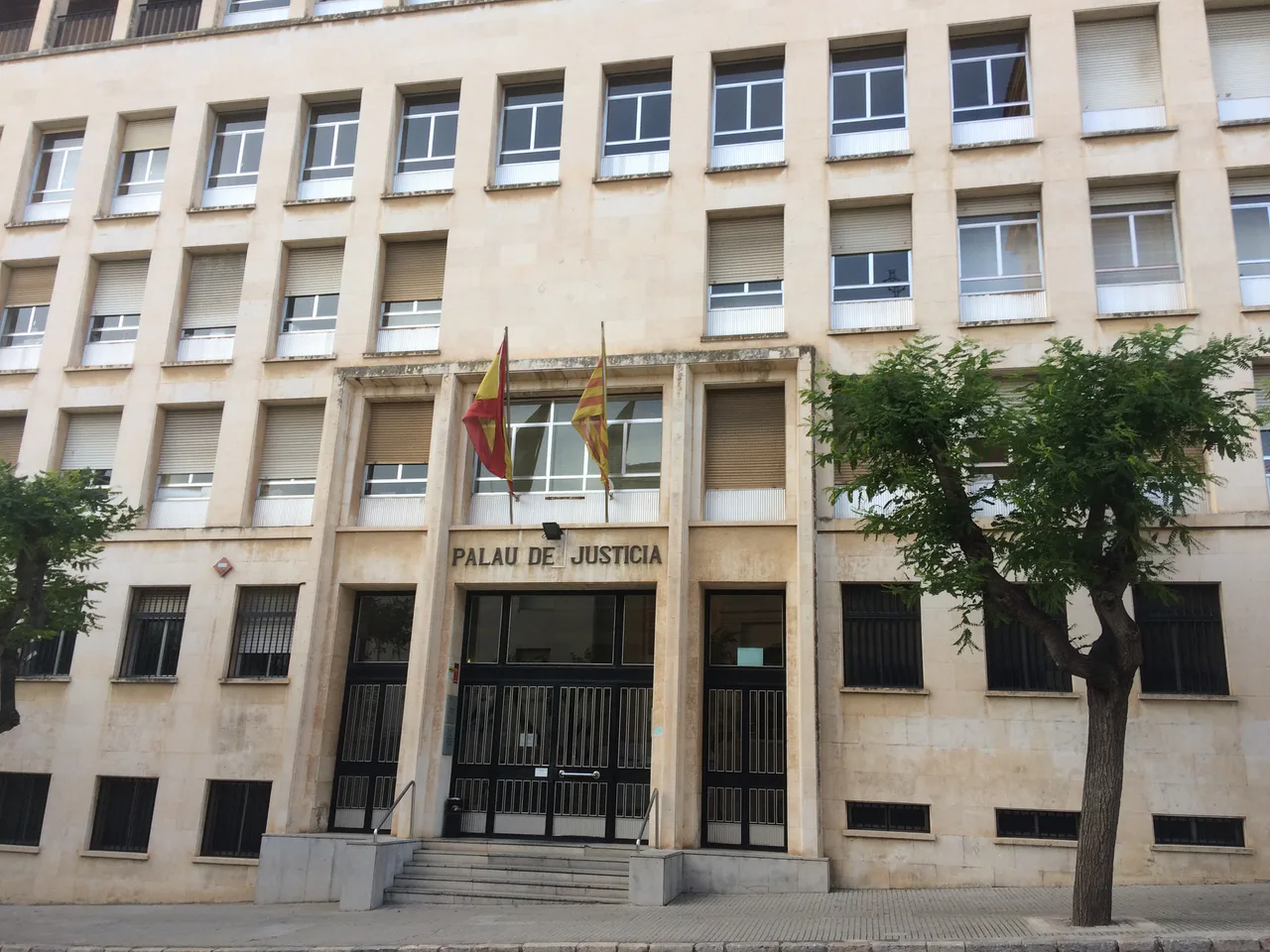 Entrance to the Palace of Justice in Tarragona, with facade sign and flags
