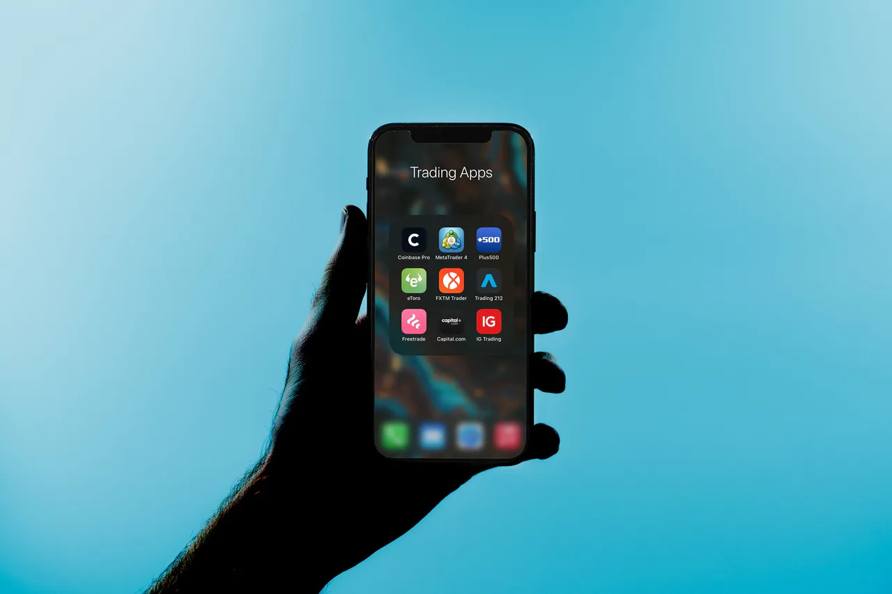 A phone displays a folder containing financial trading apps.