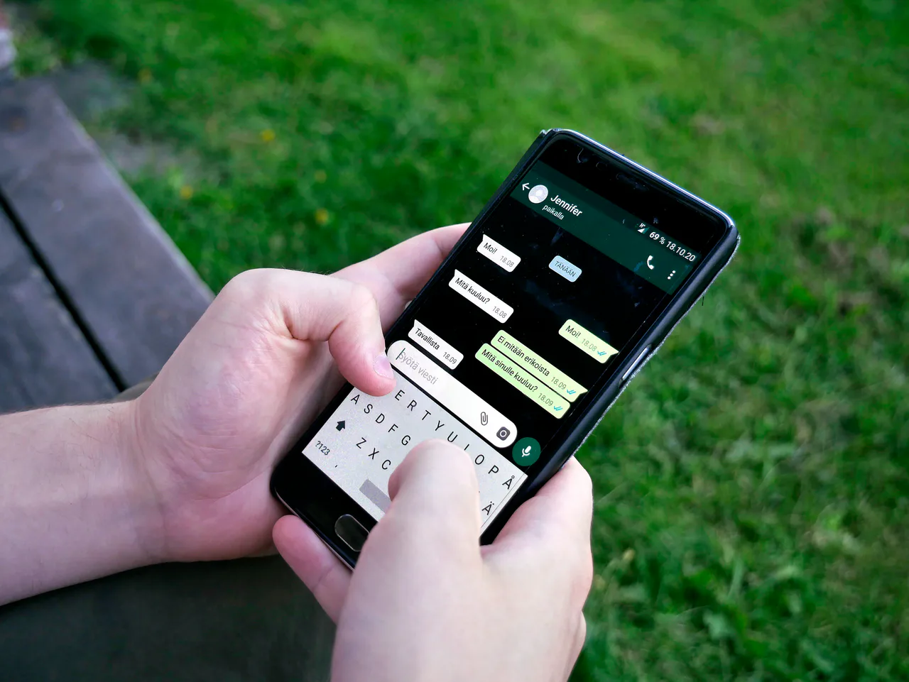 Manos utilizando WhatsApp en un teléfono al aire libre