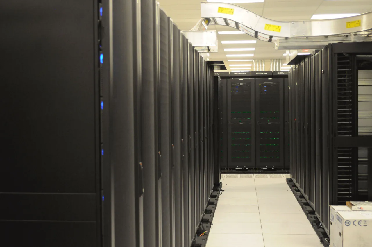 A corridor between server racks beneath overhead cabling.