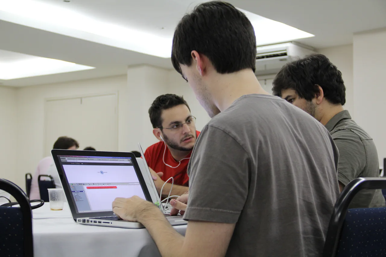 Participantes trabajan alrededor de un portátil durante Startup Weekend Recife.