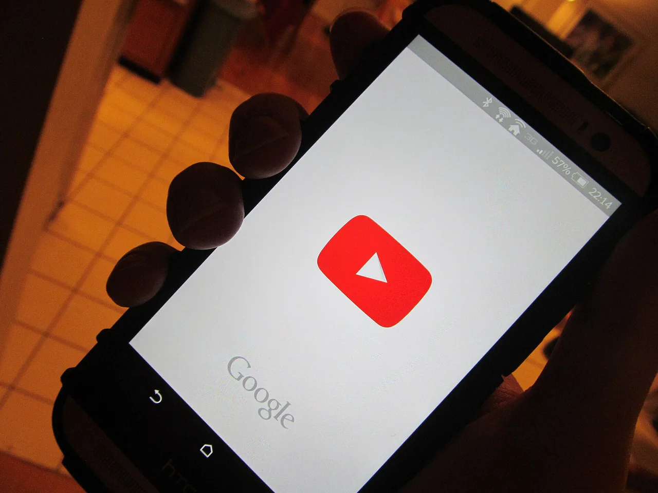Una mano sostiene un teléfono con YouTube abierto.